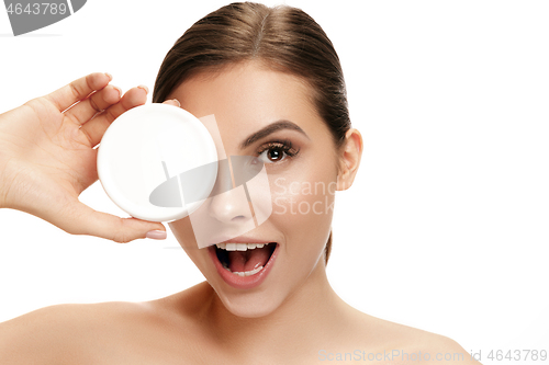 Image of Cute girl preparing to start her day. She is applying moisturizer cream on face.