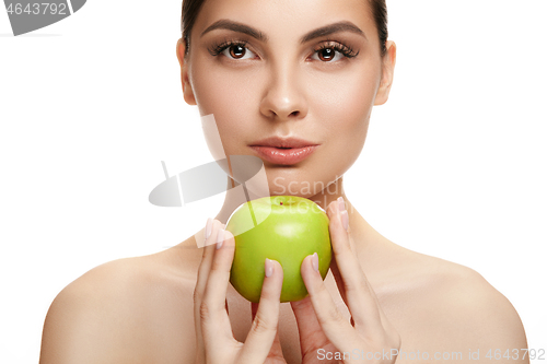 Image of portrait of attractive caucasian smiling woman isolated on white studio shot eating green apple