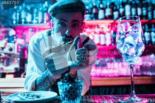 Image of Expert barman is making cocktail at night club.