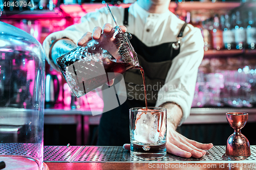 Image of Expert barman is making cocktail at night club.