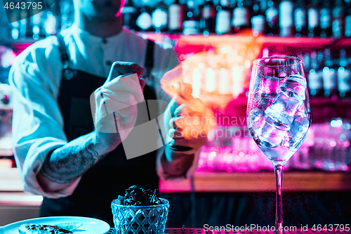 Image of Expert barman is making cocktail at night club.