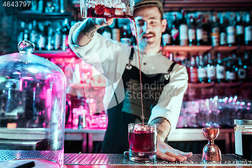 Image of Expert barman is making cocktail at night club.