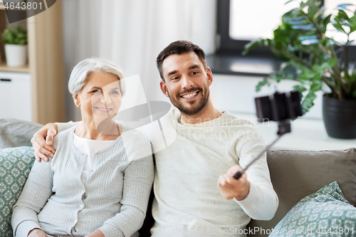 Image of senior mother with adult son taking selfie at home