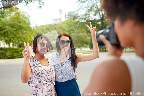 Image of woman photographing her friends in summer park