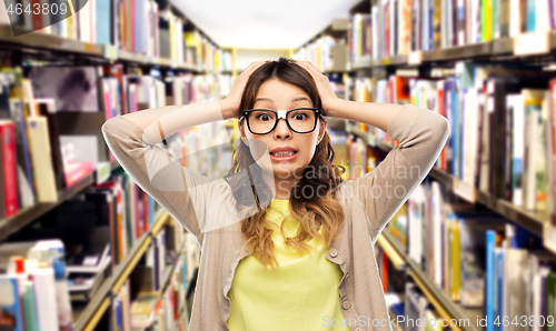 Image of asian female student holding to head at library