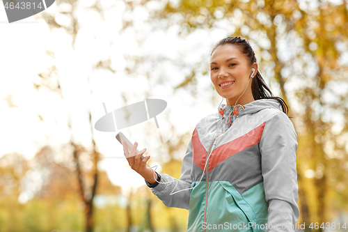 Image of woman in autumn park and listening to music