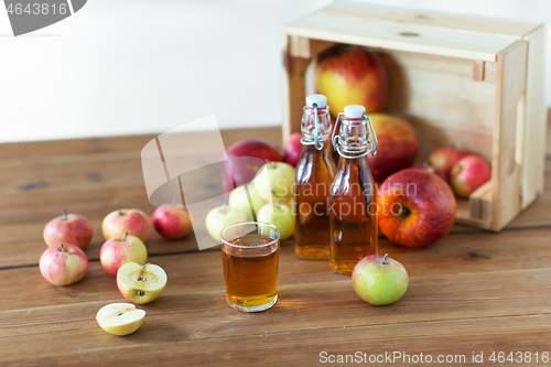 Image of glass and bottles of apple juice on wooden table