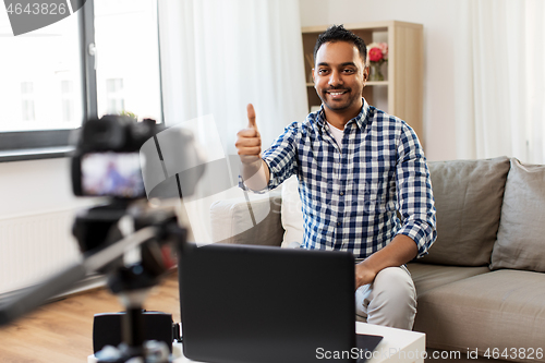 Image of male blogger with camera videoblogging at home