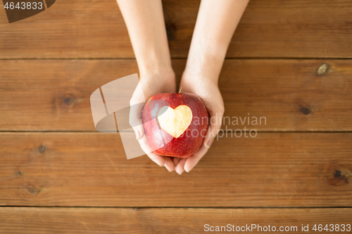 Image of close up of hands holding apple with carved heart