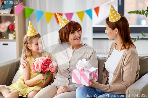 Image of mother with gift greeting grandmother on birthday