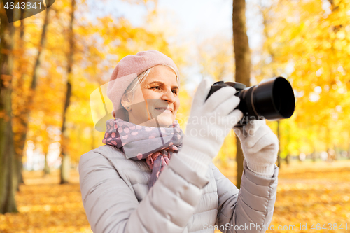 Image of senior woman with photo camera at autumn park
