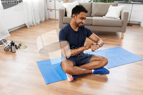 Image of smiling indian man with fitness tracker at home