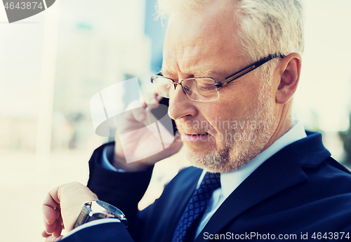 Image of senior businessman calling on smartphone in city