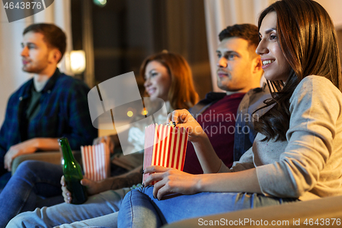 Image of friends with beer and popcorn watching tv at home