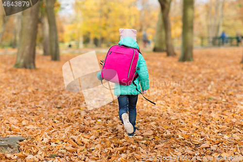 Image of little girl with school bag at autumn park