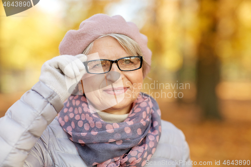 Image of portrait of happy senior woman at autumn park