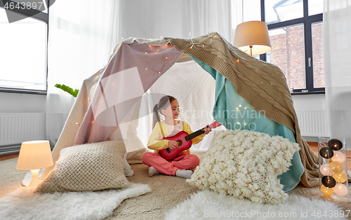 Image of little girl playing guitar in kids tent at home