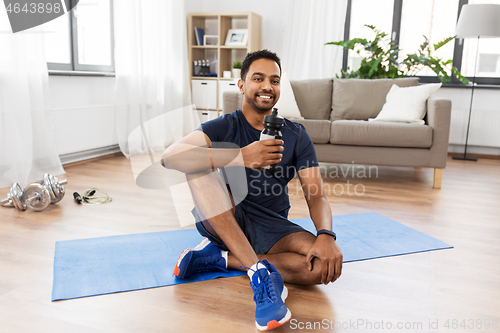 Image of indian man drinking water after training at home