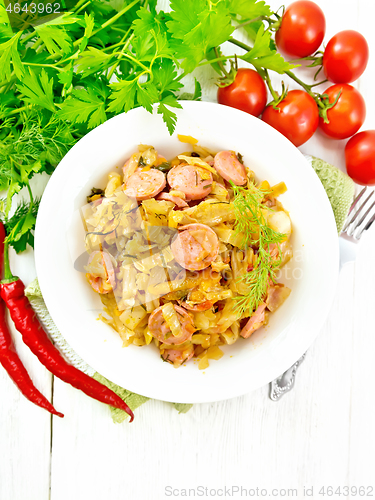 Image of Cabbage stew with sausages in white plate on board top