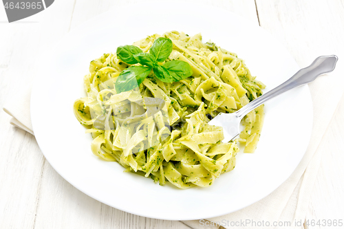 Image of Pasta with pesto sauce in plate on wooden board