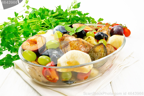 Image of Chicken with fruits and tomatoes in pan on wooden board