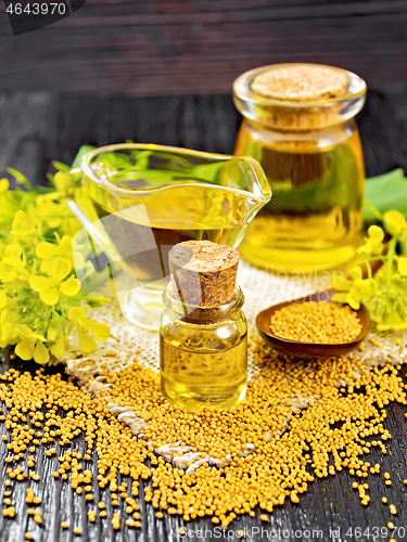 Image of Oil mustard in two jars and gravy boat on dark wooden board