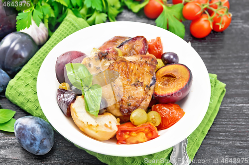 Image of Chicken with fruits and tomatoes in plate on dark board