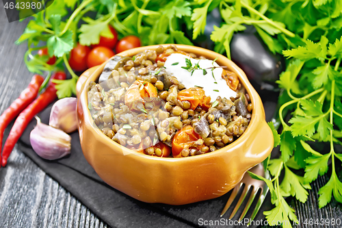 Image of Lentils with eggplant and tomatoes in bowl on dark board 