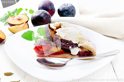 Image of Galeta with plums in plate on light wooden board