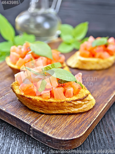 Image of Bruschetta with tomato and basil on dark board