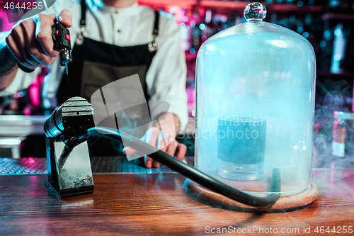 Image of Expert barman is making cocktail at night club.