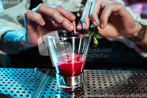 Image of Expert barman is making cocktail at night club.