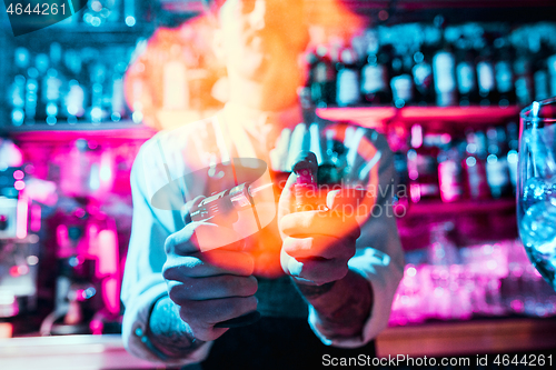 Image of Expert barman is making cocktail at night club.