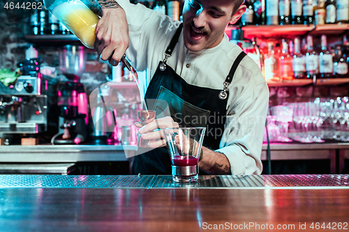 Image of Expert barman is making cocktail at night club.