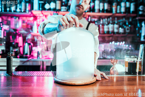 Image of Expert barman is making cocktail at night club.