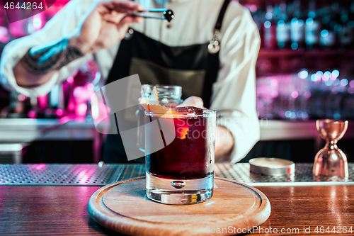 Image of Expert barman is making cocktail at night club.