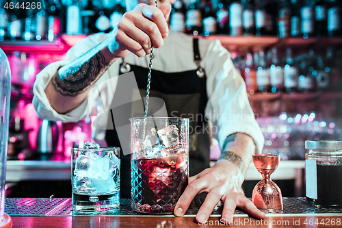 Image of Expert barman is making cocktail at night club.