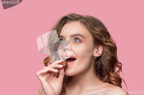 Image of beauty portrait of a cute girl in act to eat a chocolate candy