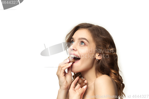 Image of beauty portrait of a cute girl in act to eat a chocolate candy