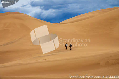 Image of Travelers in desert dunes in mountains