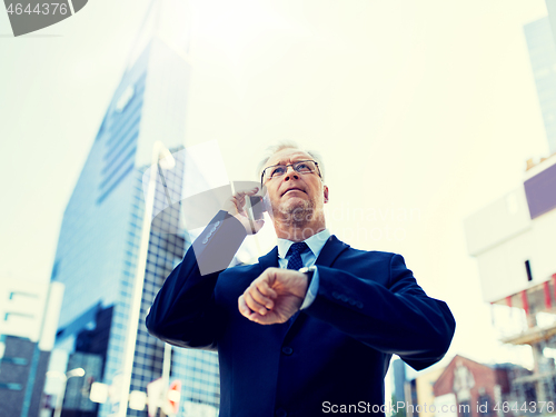 Image of senior businessman calling on smartphone in city