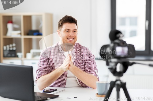 Image of male blogger with camera videoblogging at home