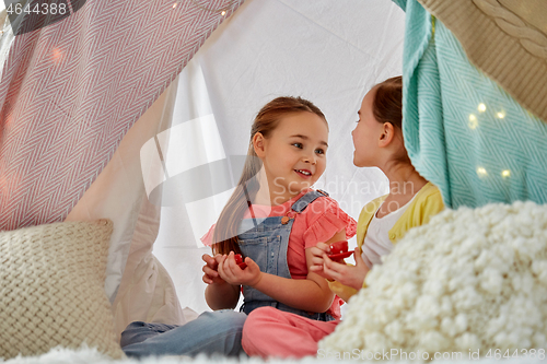 Image of little girl playing tea party in kids tent at home