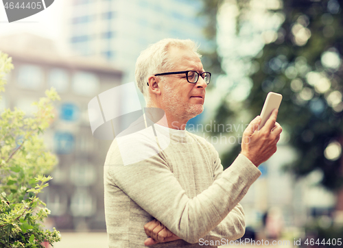 Image of senior man texting message on smartphone in city