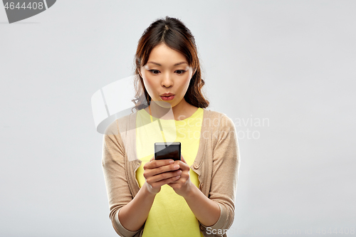 Image of surprised asian woman using smartphone