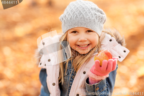 Image of happy little girl with apple at autumn park