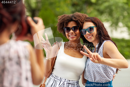 Image of woman photographing her friends in summer park