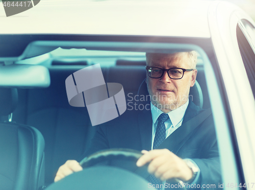 Image of happy senior businessman driving car