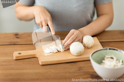 Image of woman cutting champignons by knife on board