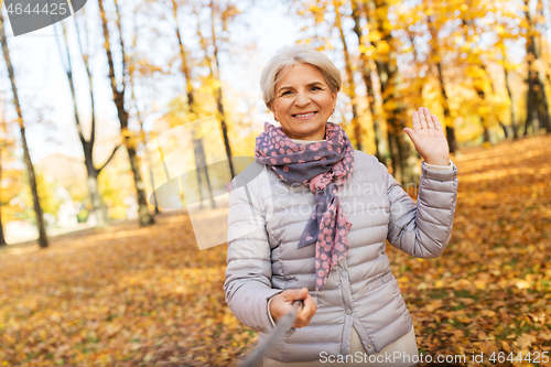 Image of senior woman taking selfie at autumn park